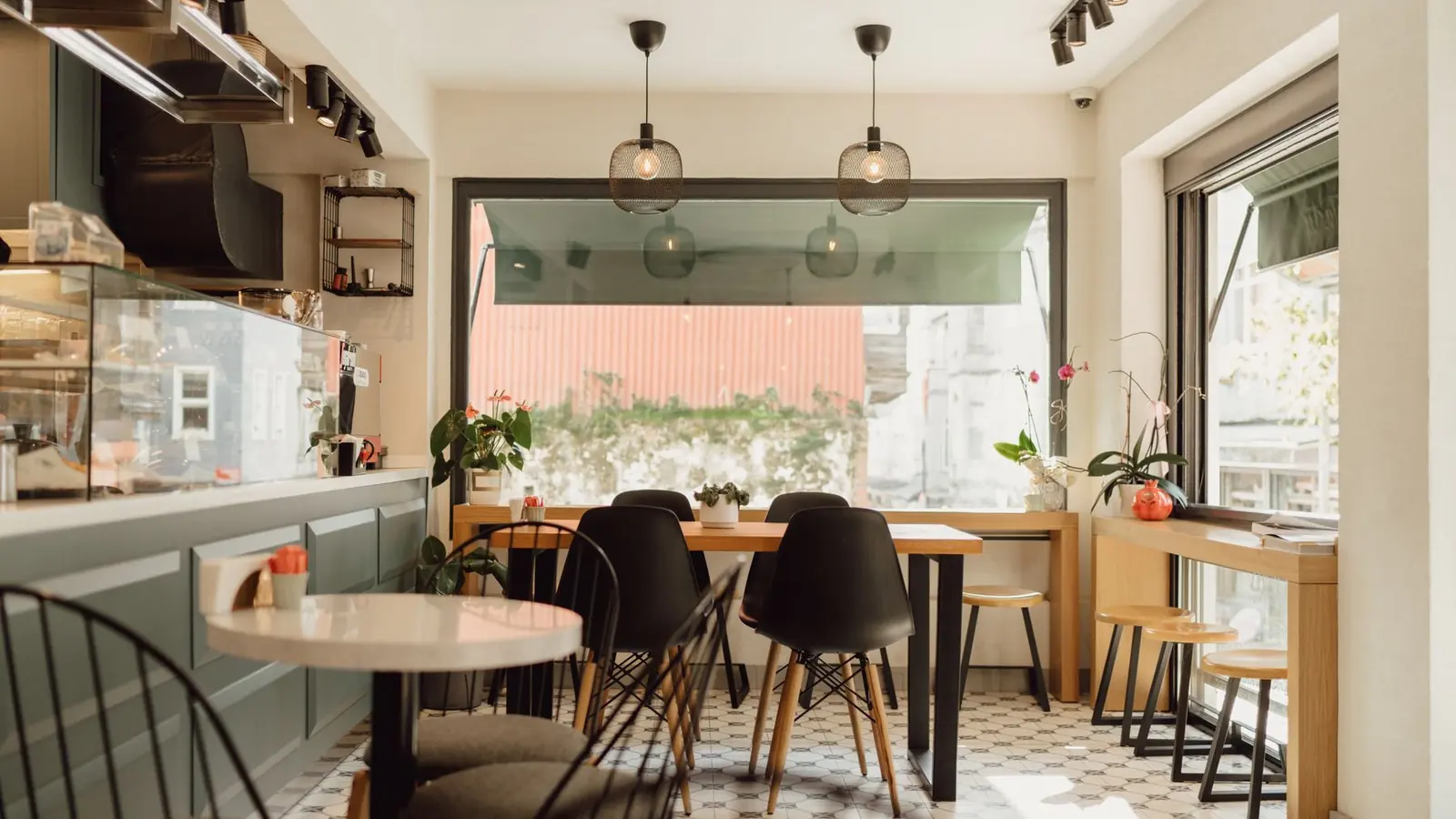 Interior de café vazio, com balcão, vitrine refrigerada e mesas junto à janela