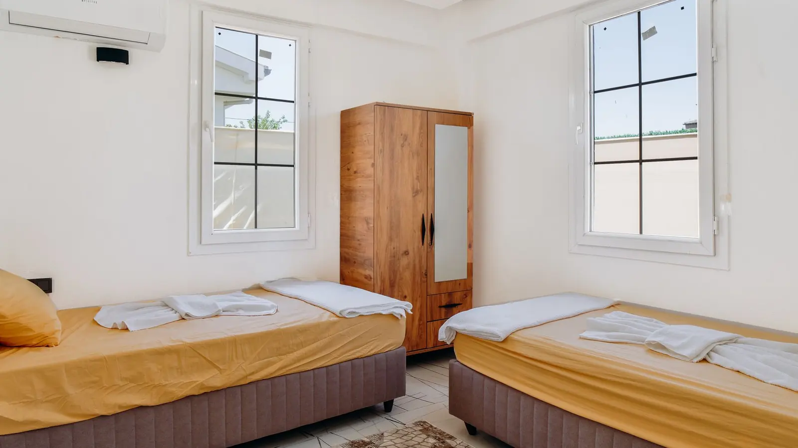Quarto de hotel vazio com duas camas e uma unidade de ar condicionado na parede